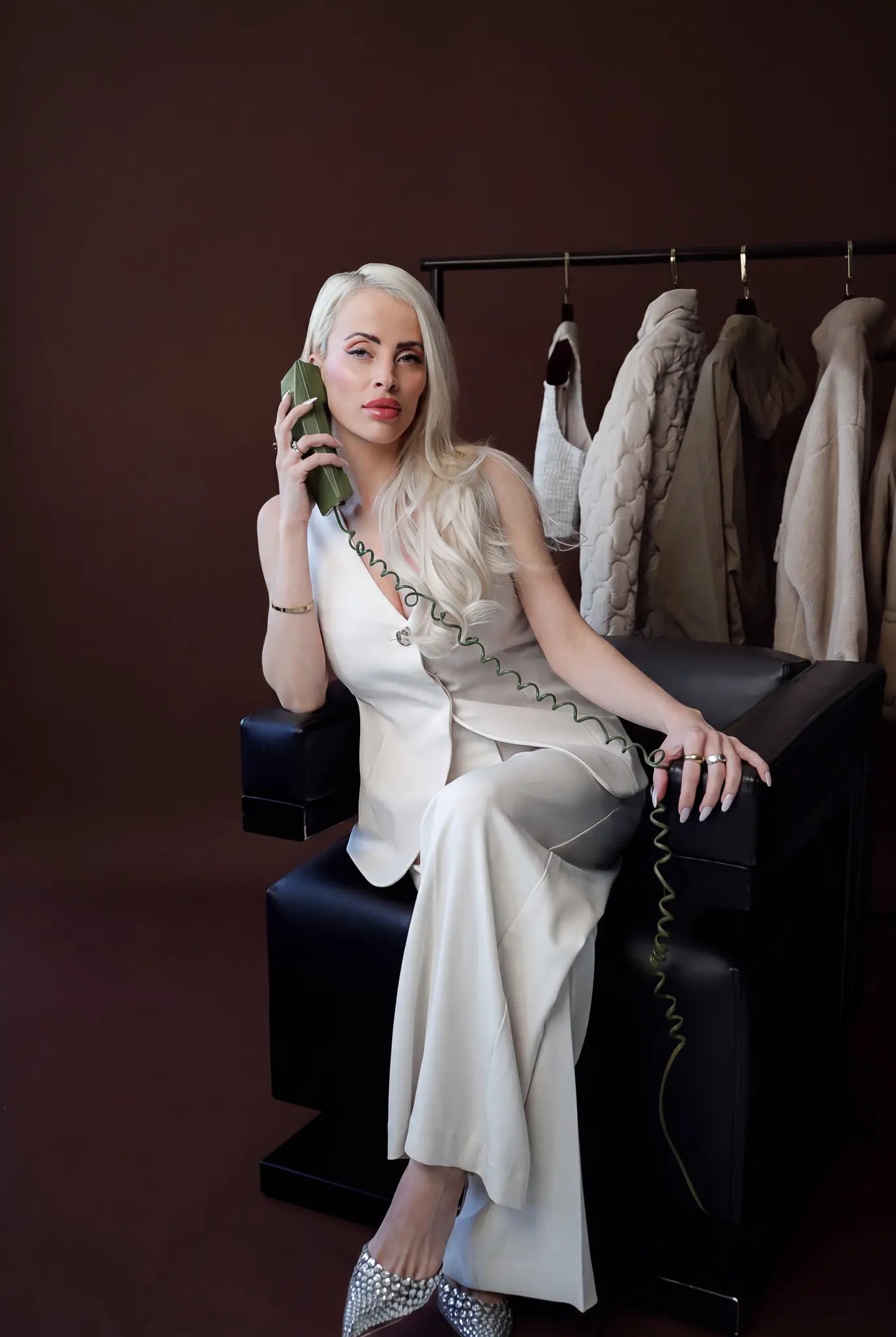 Bianca Da Silva seated beside a rail of sourced garments, reflecting her retail buying and product sourcing work